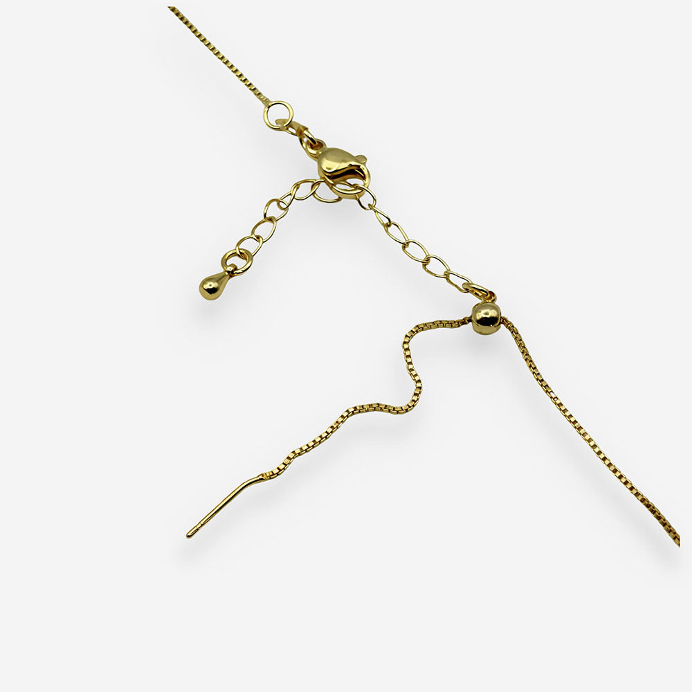 Detalle de collar con colgante irregular dorado y cristal central complementando un look elegante.