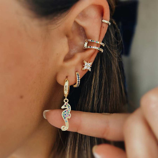 Oreja de mujer con ear party de aretes doradas y Candongas doradas con dijes de caballitos de mar