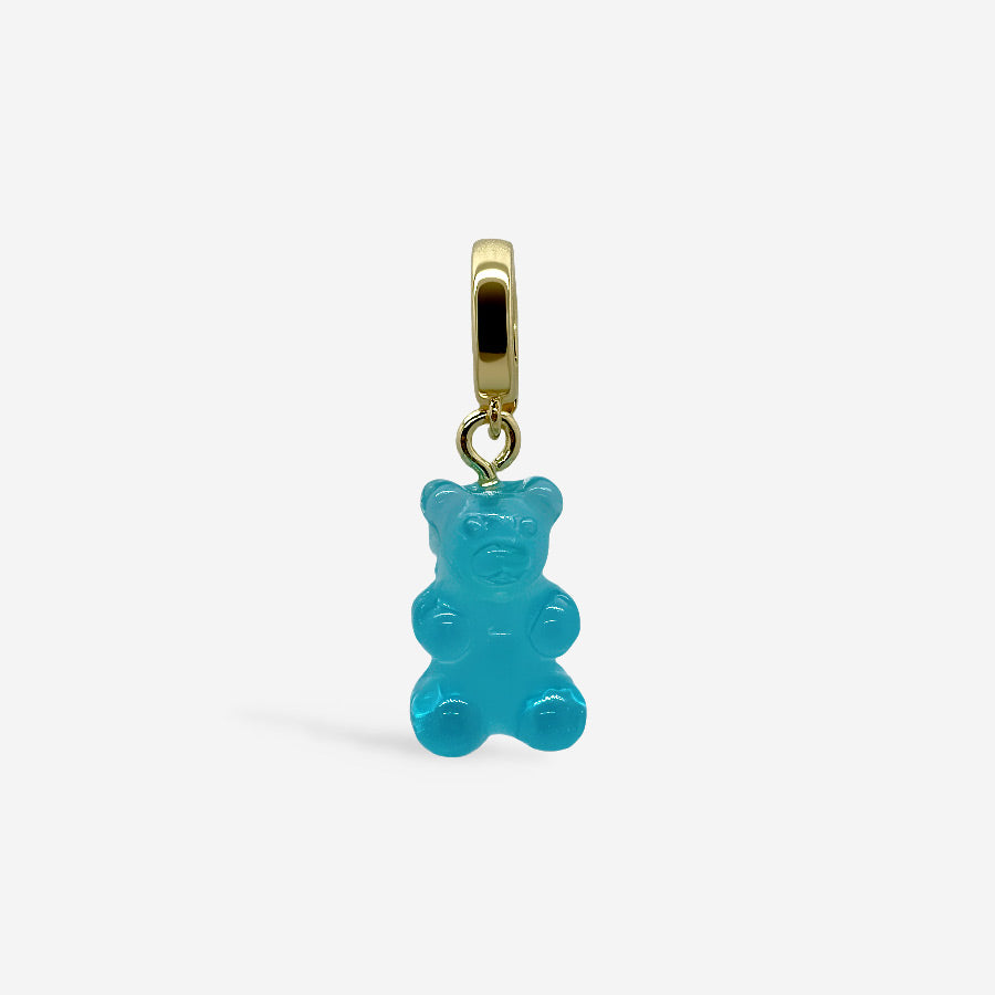 Dije osito de goma azul con broche dorado, sobre fondo blanco.