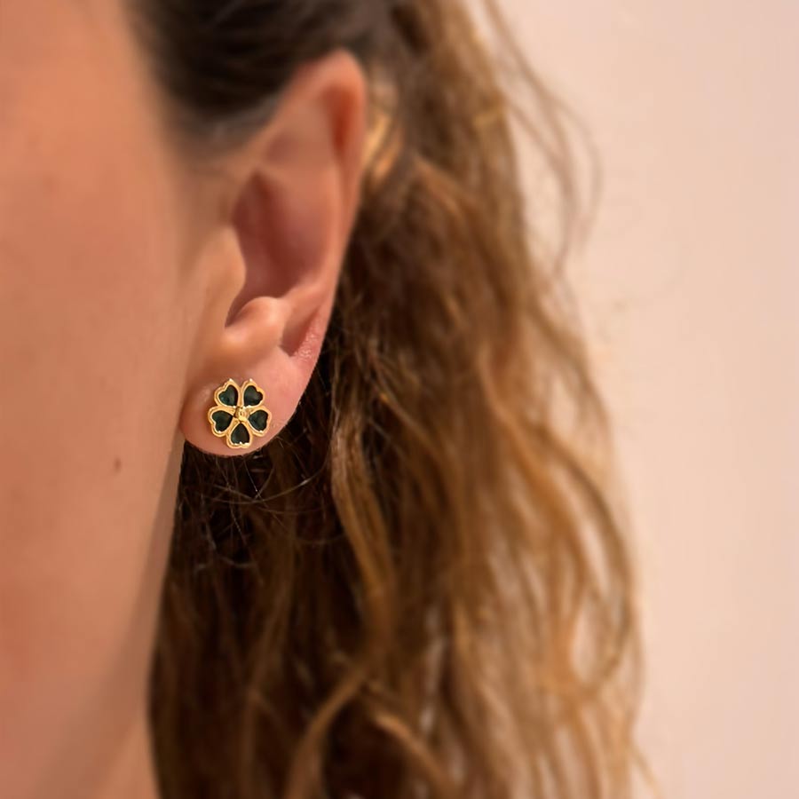 Accesorio mini topitos trébol verde sobre la oreja de una mujer
