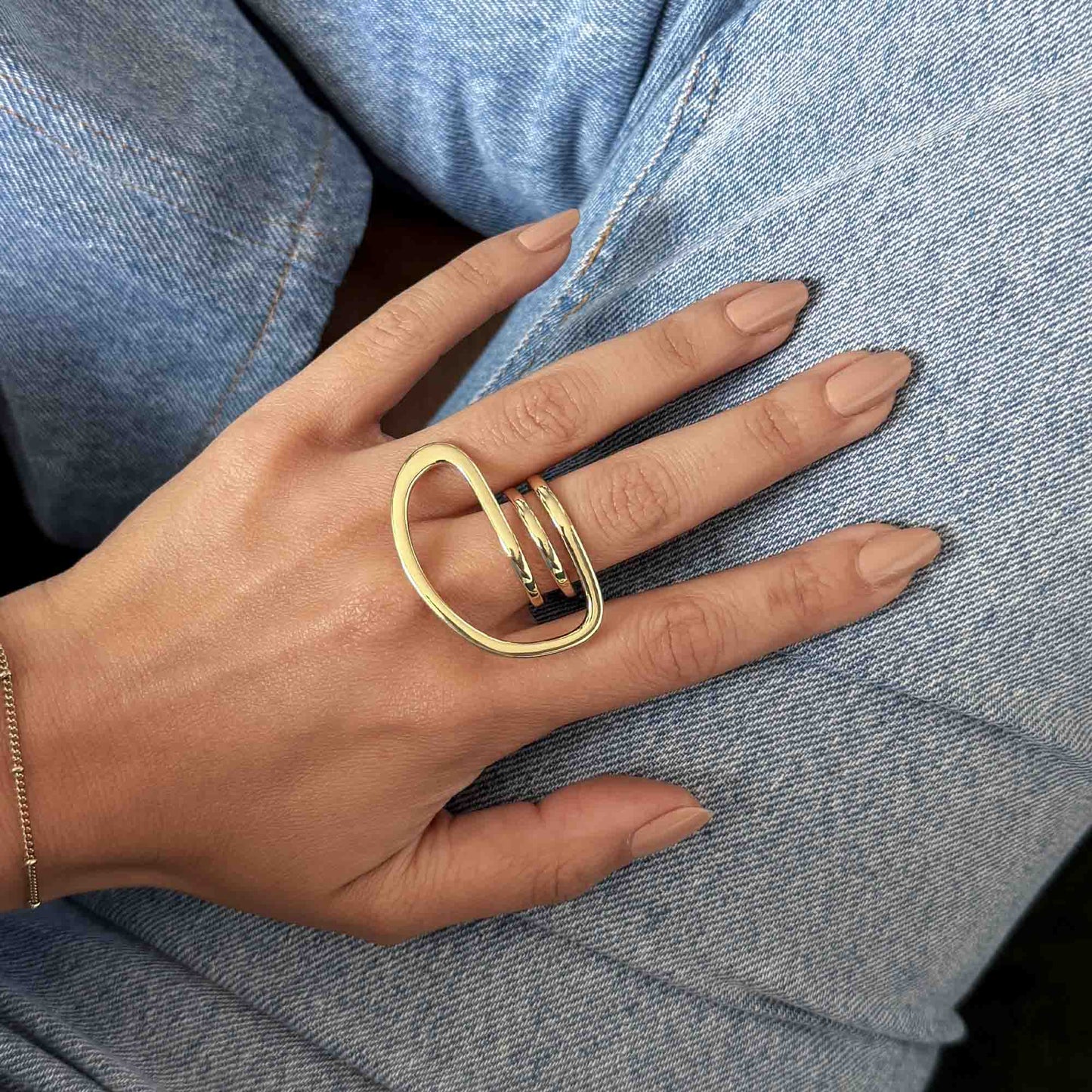 Anillo statement dorado con diseño orgánico puesto en el dedo