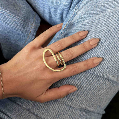 Anillo statement dorado con diseño orgánico puesto en el dedo