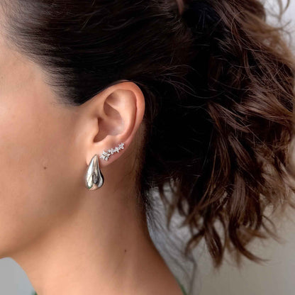 Aretes tipo lágrima con baño de rodio puestos en la oreja