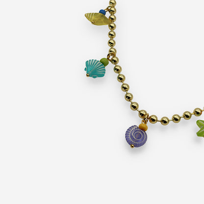 Collar ajustable elaborado en bronce con baño de oro de 18K y dijes marinos multicolor unidos con alambre de golfi.