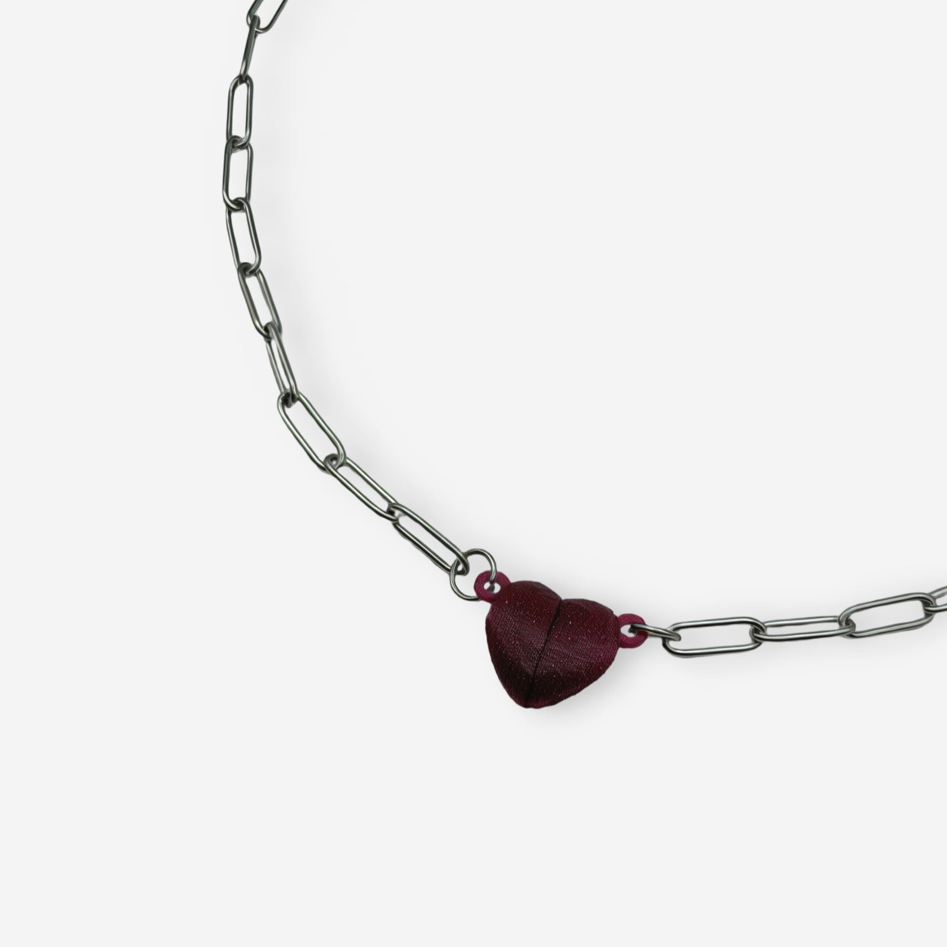 Detalle del broche magnético en forma de corazón impreso en 3D en color vinotinto sobre cadena clip dorada