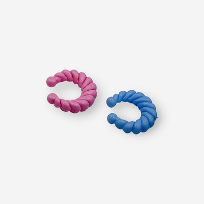 Earcuff estilo twist disponible en tonos rosa y azul para complementar looks modernos y divertidos.