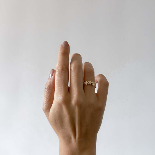 Mano de mujer con un anillo dorado con flores 