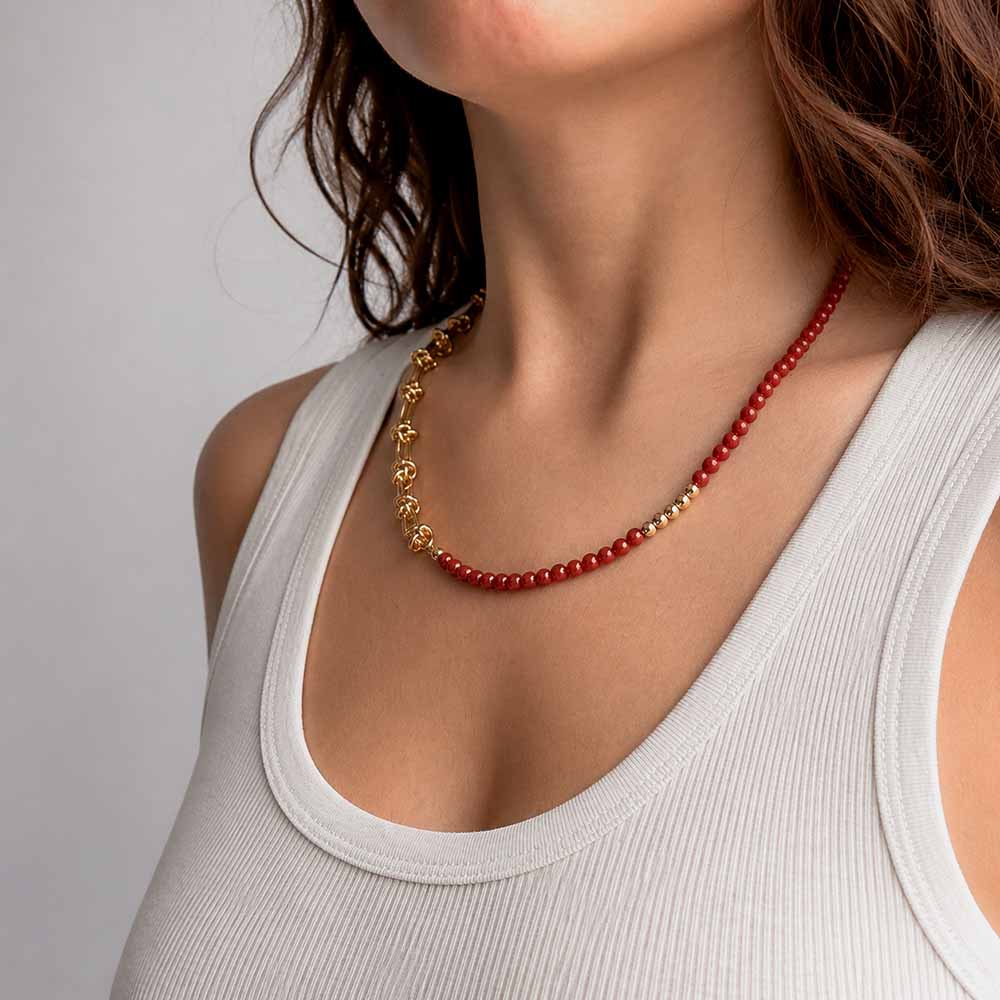 Mujer llevando collar de piedra natural cornalina roja combinado con detalles dorados como pieza protagonista del outfit.