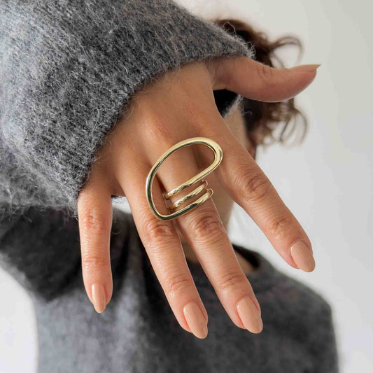 Mujer usando anillo escultural dorado de gran tamaño sobre la mano
