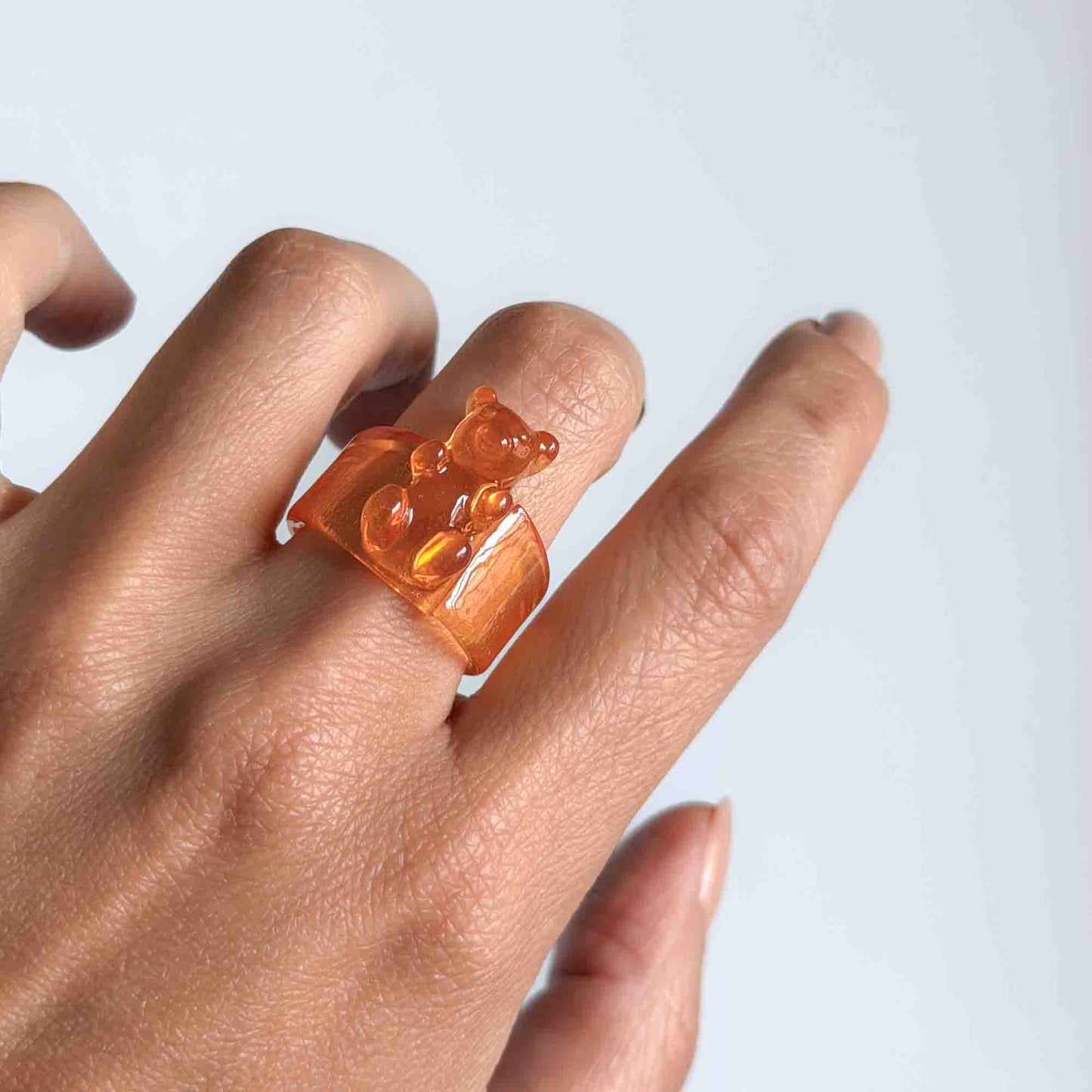 Mujer usando anillo naranja de osito en resina transparente