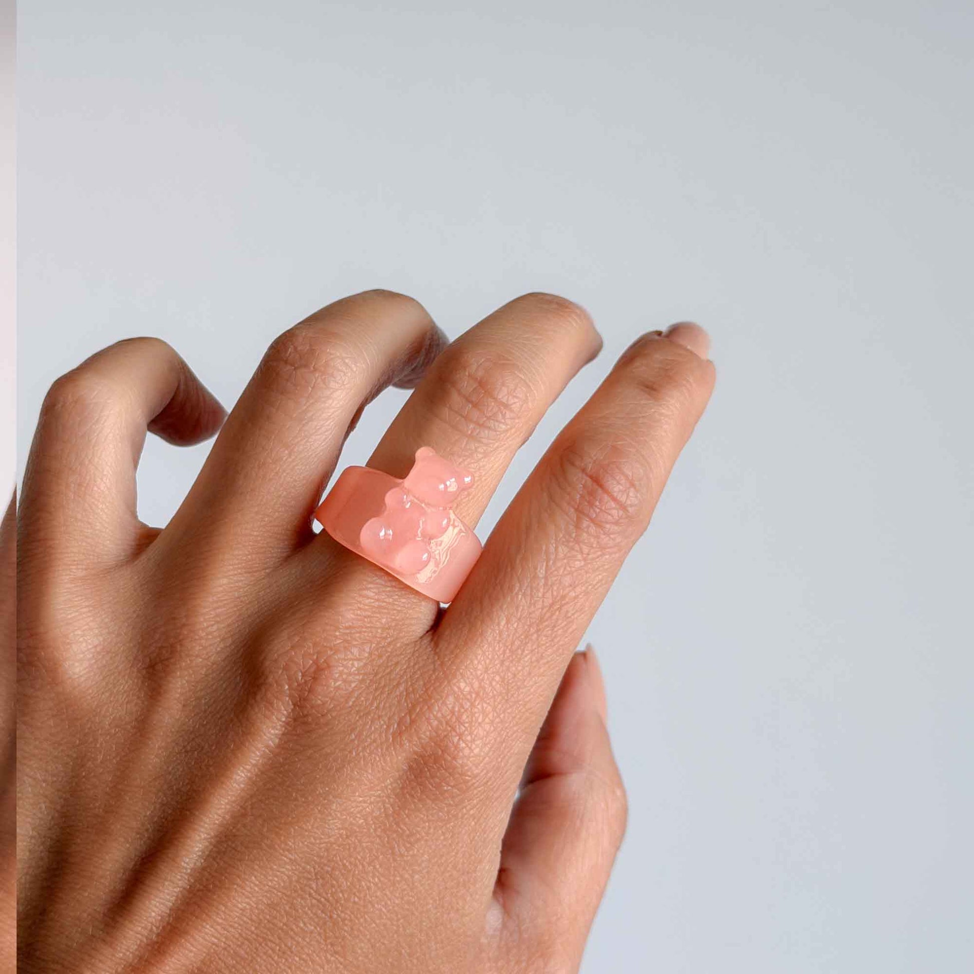 Mujer usando anillo rosa de osito en resina transparente