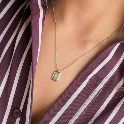 Mujer usando collar con dije rectangular y circonia central para mostrar su tamaño y caída sobre el escote.