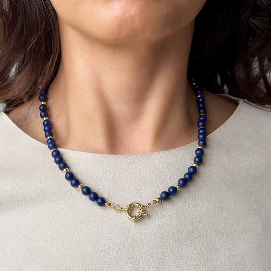 Mujer usando collar de lapislázuli natural azul para mostrar su caída y proporción sobre el escote.