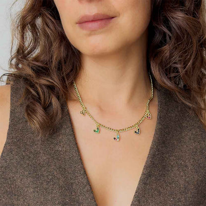 Mujer usando collar dorado con dijes de corazones y circonias multicolor para mostrar su ajuste sobre el cuello.