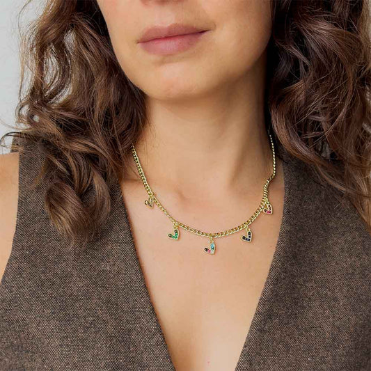 Mujer usando collar dorado con dijes de corazones y circonias multicolor para mostrar su ajuste sobre el cuello.