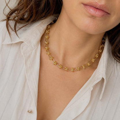 Mujer usando collar dorado de eslabones con nudos para mostrar su ajuste y caída sobre el cuello.