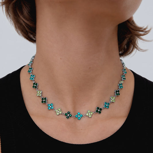 Mujer usando un collar plateado de tréboles con circonias verdes
