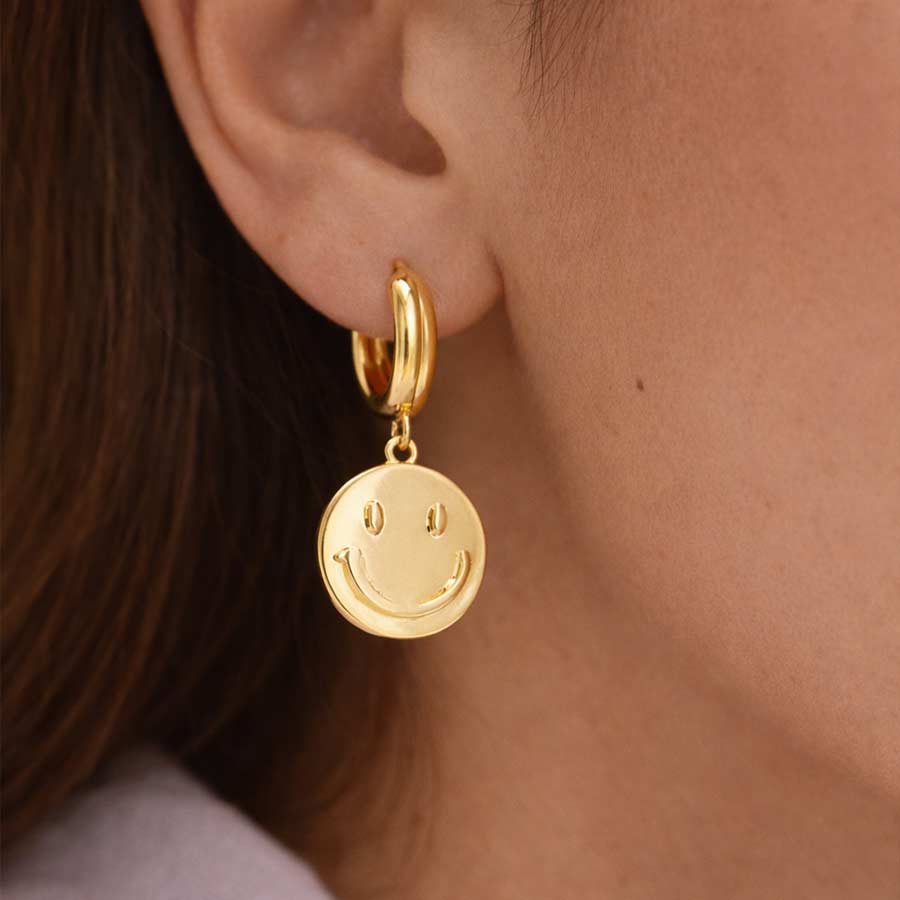 Mujer con Candongas doradas con dije smiley colgante