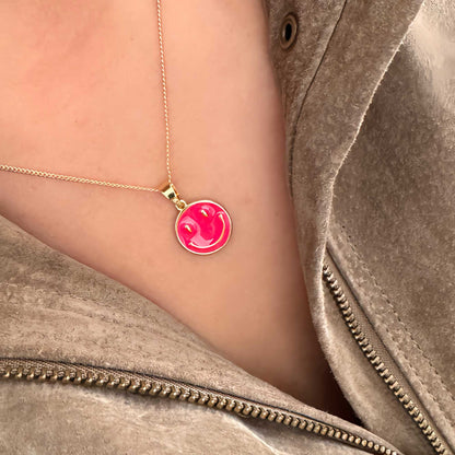 Detalle de collar dorado con dije esmaltado magenta