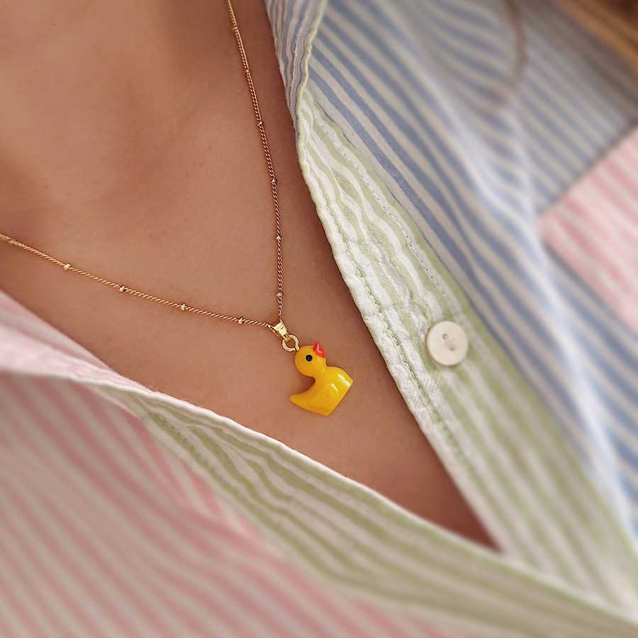 mujer con camisa de raya de colores con collar dorado con dije de pato amarillo