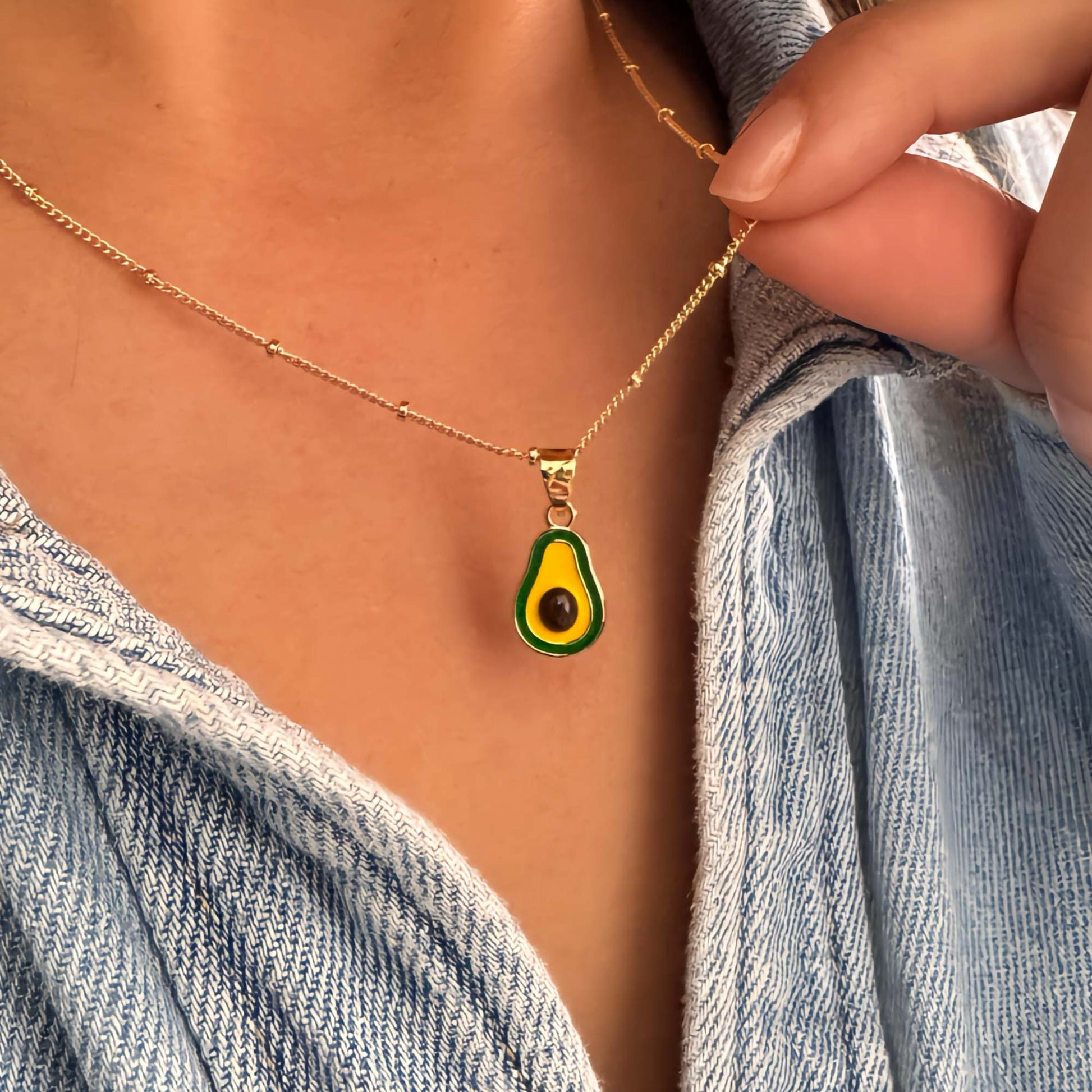 Detalle de collar dorado con dije de aguacate