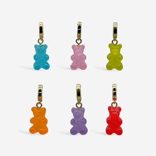 Dijes ositos de goma con broche dorado, sobre fondo blanco.