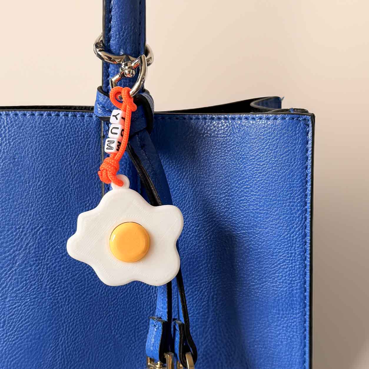 llavero  con dije de huevo frito en bolso azul 