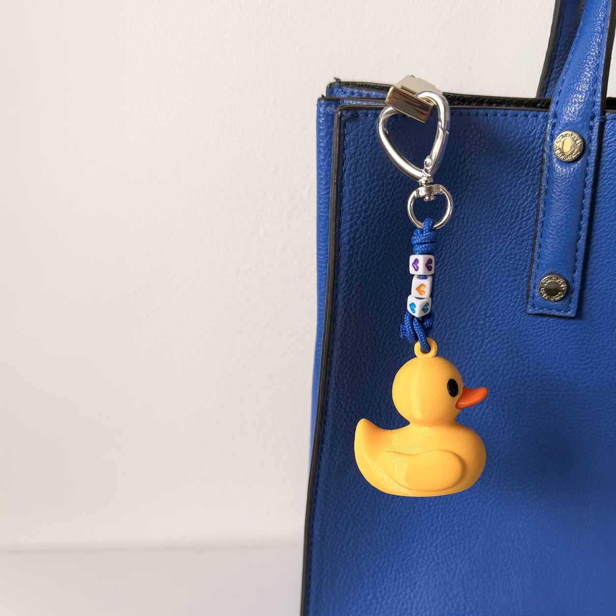 llavero de bolso con dije de pato de ule en impresión 3D de 19/86 studio en bolso azul