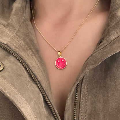 Joyería dorada con diseño de carita feliz fucsia