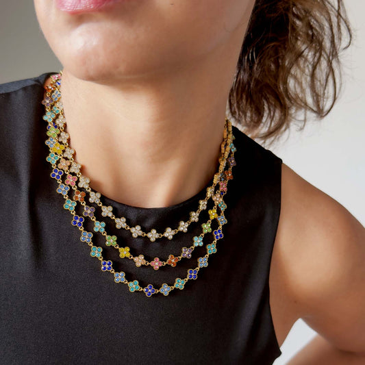 mujer usando collares dorados en acero con figuras de trebol con circonias de  colores