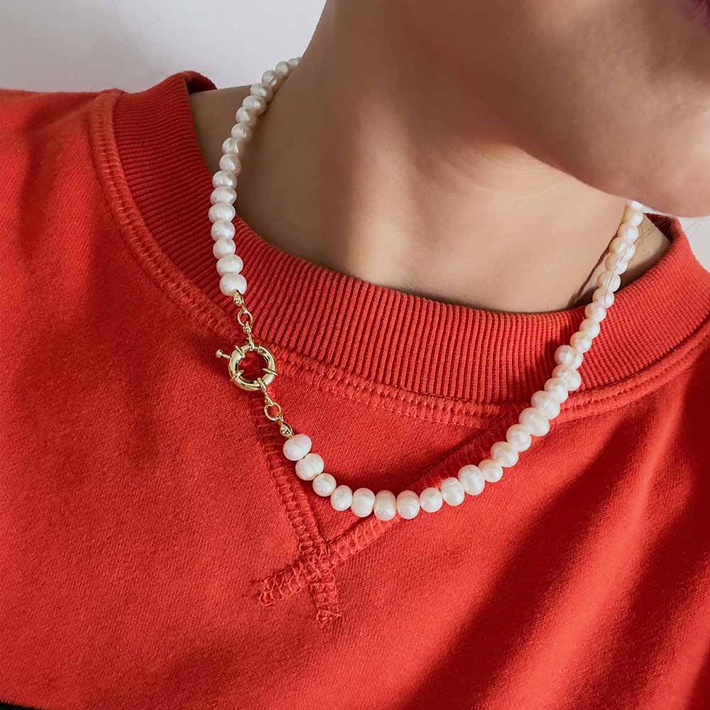 mujer usando un collar de perlas del rio con broche nautico dorado